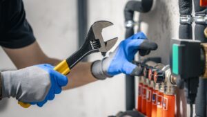 A man installs a heating system in a house and checks the pipes with a wrench.