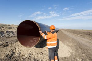 Pipeline workers measuring tube length for construction of gas and oil pipes.